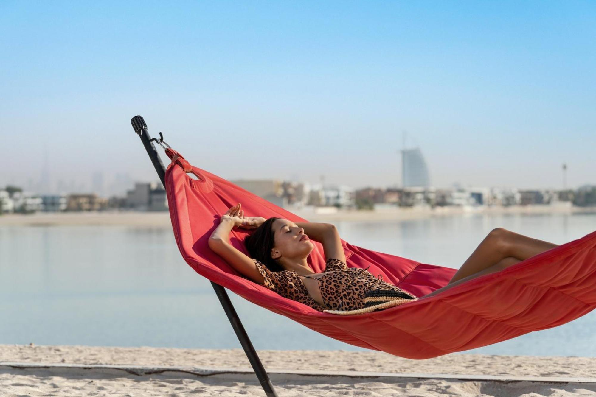 Th8 Palm Dubai Beach Resort, Vignette Collection By Ihg מראה חיצוני תמונה A woman relaxing in a hammock